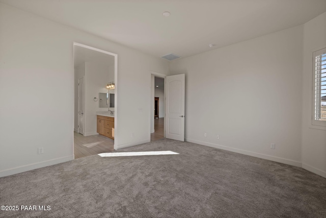 unfurnished bedroom featuring light carpet, connected bathroom, visible vents, and baseboards