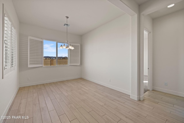 interior space featuring light wood-style floors, baseboards, and an inviting chandelier