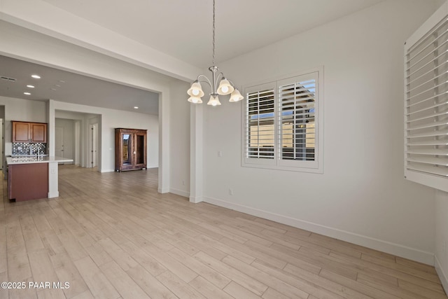 interior space with light wood finished floors, baseboards, a chandelier, and recessed lighting