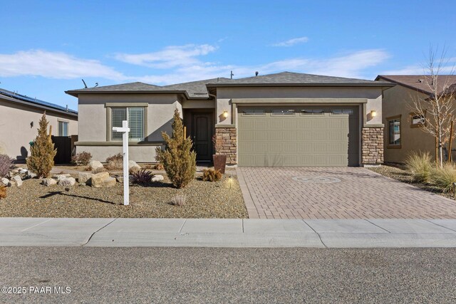 view of front of property featuring a garage, stone siding, driveway, and stucco siding