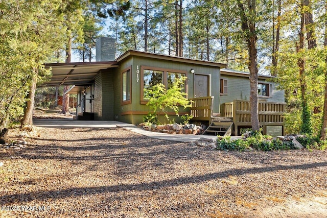 view of front facade with a deck, a chimney, and a carport