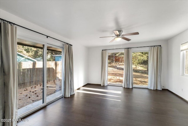 empty room with baseboards, ceiling fan, and dark wood-style floors