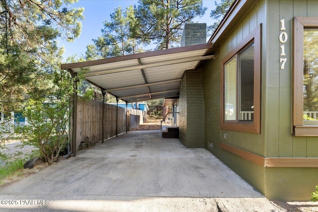 view of parking / parking lot featuring fence and a carport