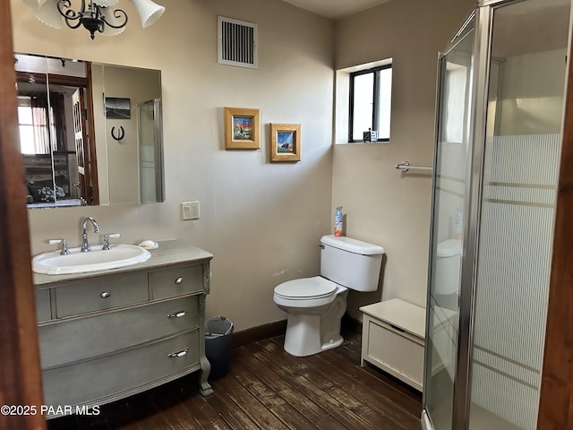 bathroom featuring vanity, wood-type flooring, an enclosed shower, and toilet