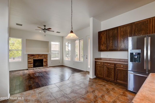 kitchen with a fireplace, stainless steel fridge, a wealth of natural light, and pendant lighting