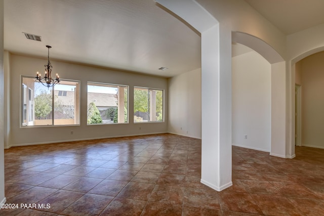 empty room with tile patterned flooring and a chandelier