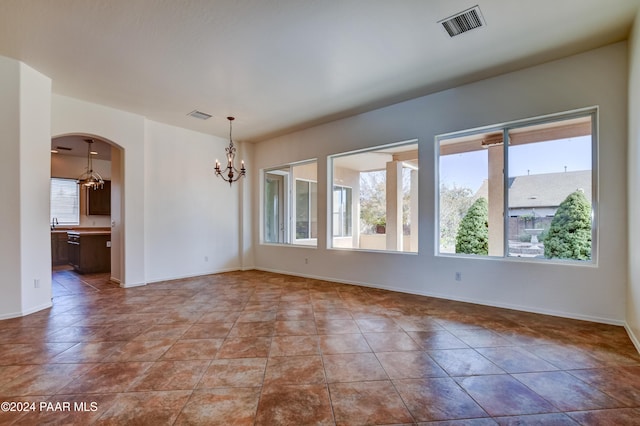 unfurnished room featuring tile patterned floors, an inviting chandelier, and a wealth of natural light