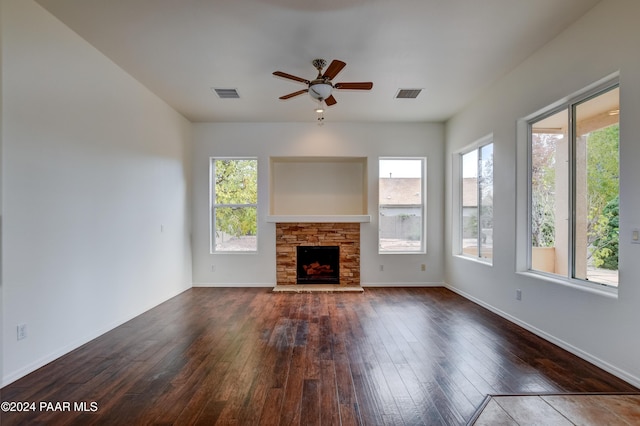 unfurnished living room featuring ceiling fan, dark hardwood / wood-style floors, and a stone fireplace