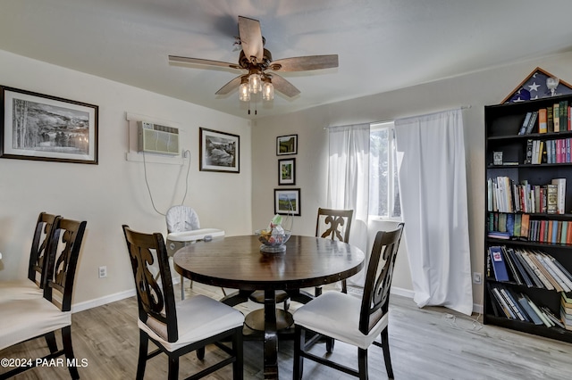 dining area with light wood-type flooring, an AC wall unit, and ceiling fan