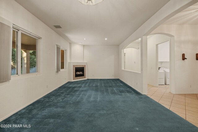 unfurnished living room featuring a fireplace, light colored carpet, and washing machine and clothes dryer