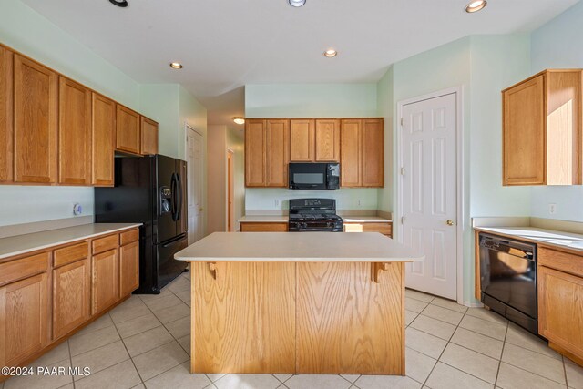 kitchen featuring black appliances, a kitchen island, light tile patterned flooring, and a kitchen bar