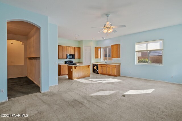 kitchen with light colored carpet, ceiling fan, sink, black appliances, and a center island