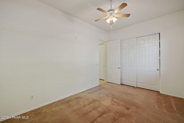 unfurnished bedroom with light carpet, a closet, and ceiling fan