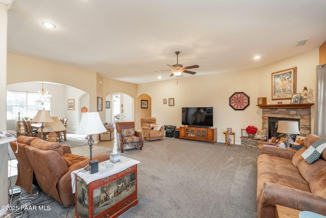 carpeted living room featuring ceiling fan with notable chandelier and a fireplace