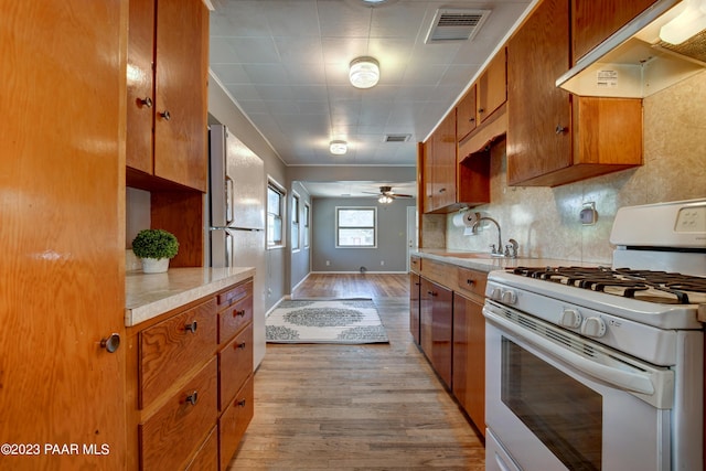 kitchen featuring light hardwood / wood-style flooring, sink, white range with gas stovetop, and decorative backsplash