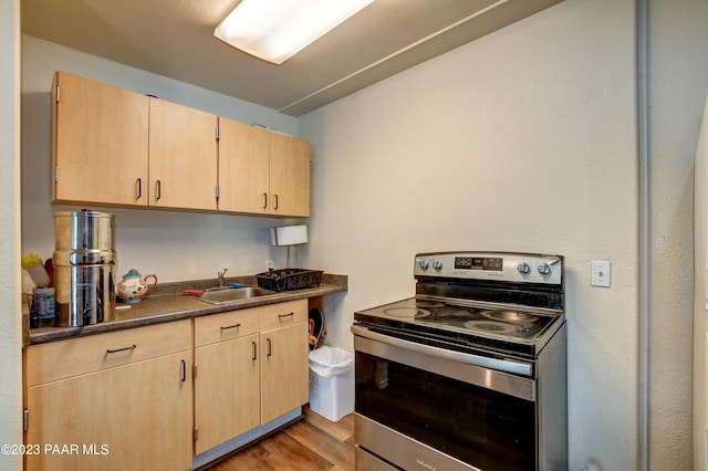 kitchen with electric stove, sink, light hardwood / wood-style floors, and light brown cabinets