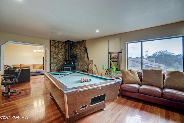 recreation room with a wood stove, light hardwood / wood-style flooring, an inviting chandelier, and billiards