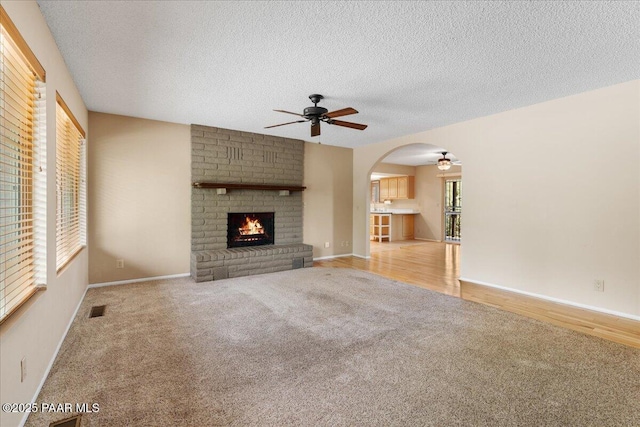 416 Hillcrest Dr, Prescott, AZ 86303 - unfurnished living room featuring ceiling fan, carpet, arched walkways, a textured ceiling, and a fireplace