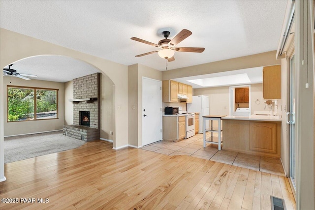 416 Hillcrest Dr, Prescott, AZ 86303 - living room with ceiling fan, light wood-style flooring, washer / clothes dryer, a brick fireplace, and arched walkways