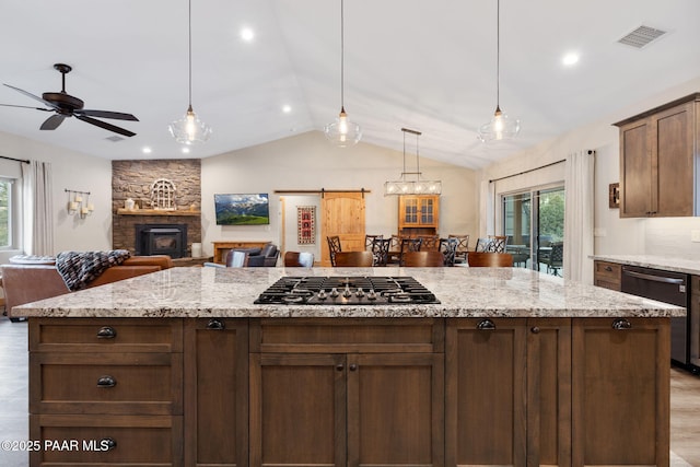 kitchen with vaulted ceiling, pendant lighting, backsplash, stainless steel appliances, and light stone countertops