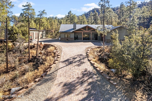 1700 S Sheriffs Posse Trl, Prescott, AZ 86303 - view of front facade with driveway, an outdoor structure, a wooded view, metal roof, and a chimney