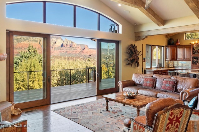 living room featuring sink, beam ceiling, hardwood / wood-style flooring, high vaulted ceiling, and a mountain view