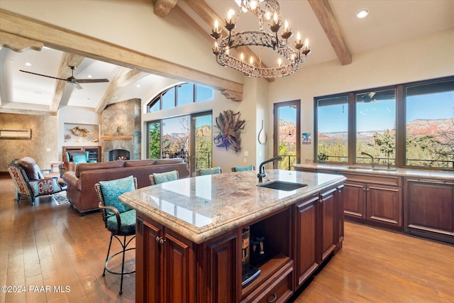 kitchen featuring a center island with sink, a fireplace, sink, and ceiling fan with notable chandelier