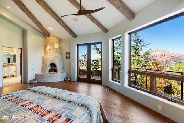 bedroom with ensuite bath, ceiling fan, access to exterior, a premium fireplace, and beamed ceiling