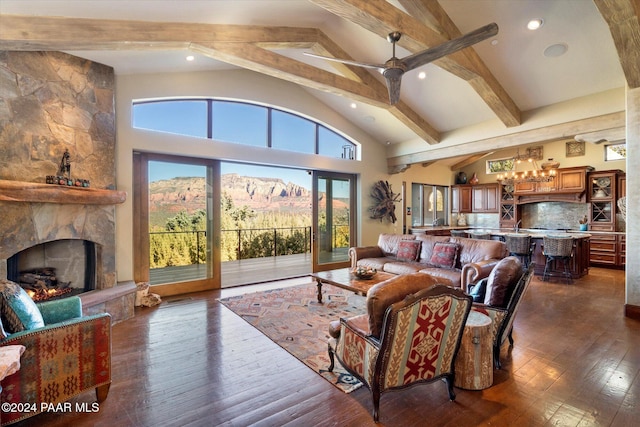 living room featuring beam ceiling, ceiling fan, dark hardwood / wood-style floors, a mountain view, and a fireplace