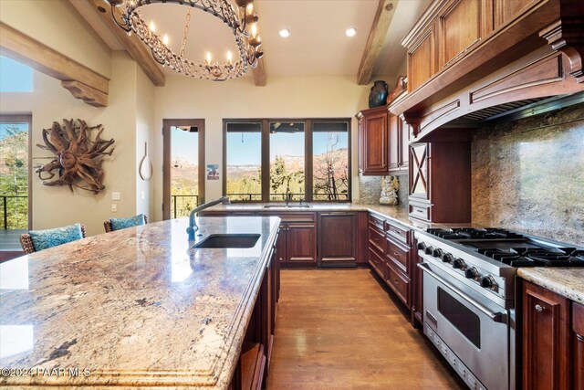 kitchen with high end range, sink, tasteful backsplash, light stone counters, and custom range hood