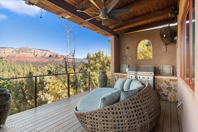 balcony with area for grilling, a mountain view, ceiling fan, and an outdoor kitchen