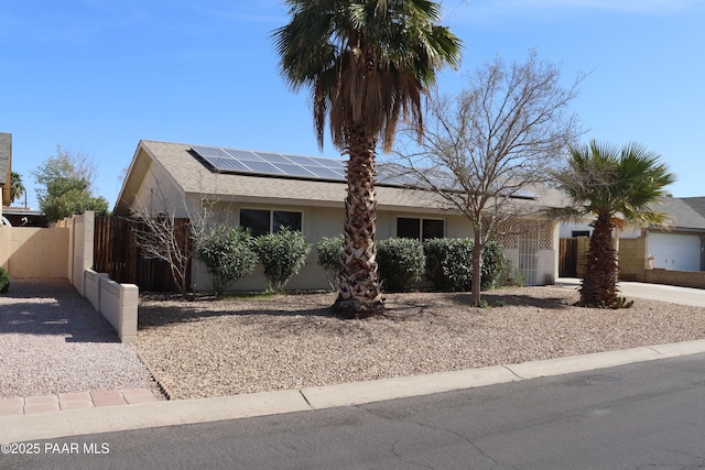 ranch-style home with solar panels, fence, a gate, and stucco siding