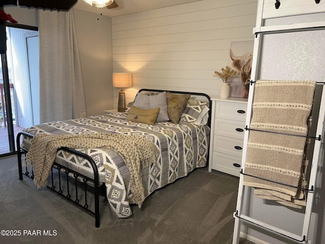 bedroom with dark colored carpet and wooden walls