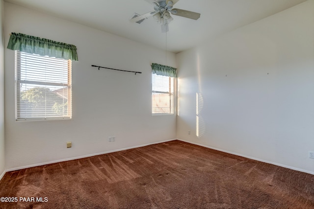 spare room with ceiling fan, a healthy amount of sunlight, and dark carpet