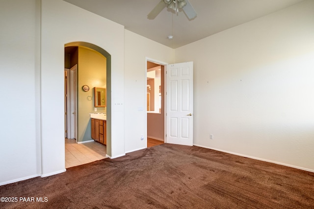 unfurnished bedroom with ceiling fan, light colored carpet, and ensuite bathroom