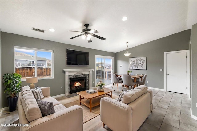 living room with a wealth of natural light, visible vents, lofted ceiling, and ceiling fan