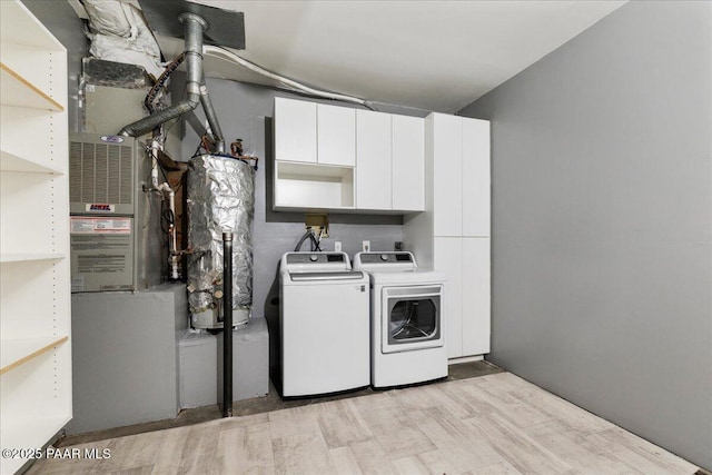 clothes washing area with cabinet space, independent washer and dryer, and light wood finished floors