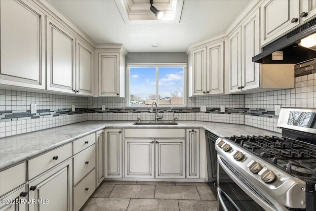 kitchen featuring under cabinet range hood, a sink, decorative backsplash, and range with two ovens