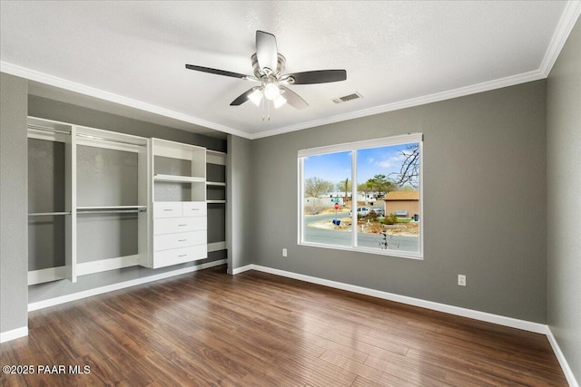 unfurnished bedroom featuring visible vents, ornamental molding, a textured ceiling, dark wood-style floors, and baseboards