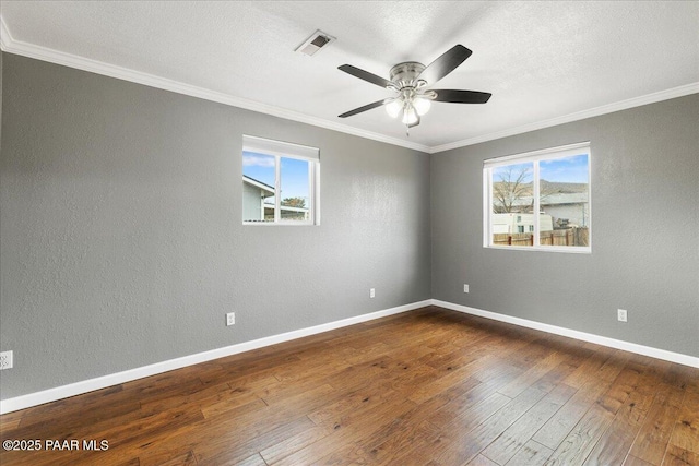 empty room featuring visible vents, baseboards, dark wood-style floors, and ornamental molding