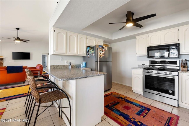 kitchen with stainless steel appliances, a kitchen breakfast bar, kitchen peninsula, white cabinets, and a raised ceiling