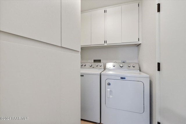 laundry area with independent washer and dryer and cabinets