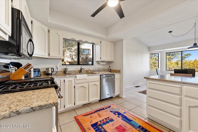 kitchen featuring light tile patterned floors, stainless steel appliances, a tray ceiling, a wealth of natural light, and white cabinets