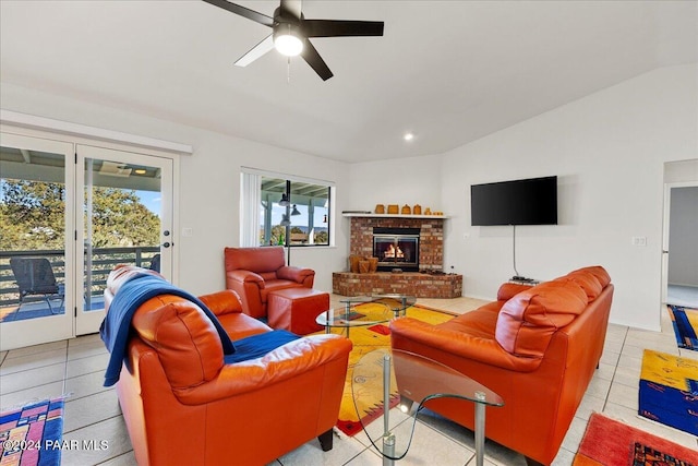 living room featuring lofted ceiling, a brick fireplace, light tile patterned floors, and ceiling fan