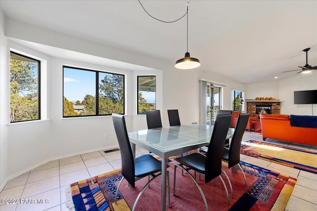 tiled dining space featuring a fireplace and ceiling fan