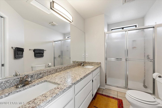 bathroom with a shower with door, vanity, tile patterned floors, and toilet