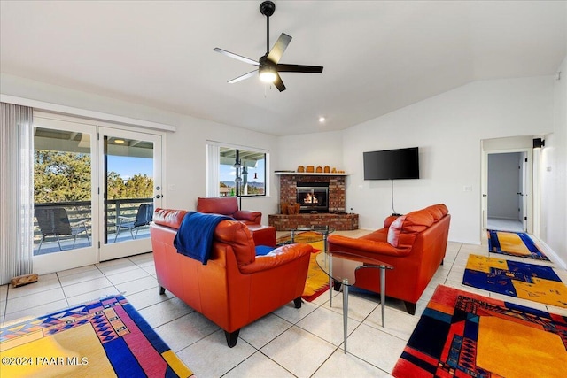 living room featuring vaulted ceiling, a brick fireplace, light tile patterned flooring, and ceiling fan