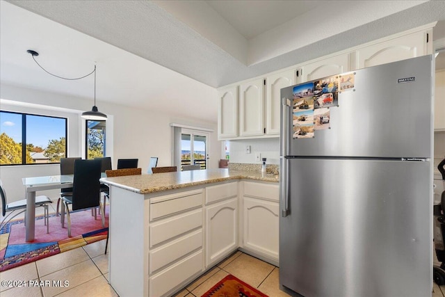 kitchen featuring white cabinets, stainless steel refrigerator, and kitchen peninsula