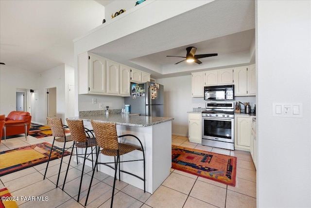 kitchen featuring ceiling fan, stainless steel appliances, white cabinets, a kitchen bar, and kitchen peninsula