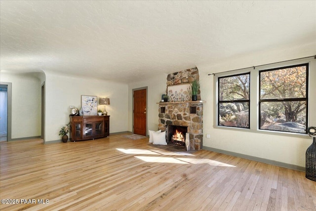 unfurnished living room with a fireplace, a textured ceiling, and light wood-type flooring